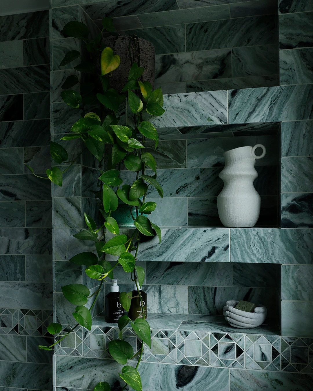 Recessed green marble bathroom shelving inspired by ancient Roman baths